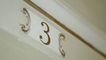 A close-up of a white wall with the number "3" and decorative swirls.