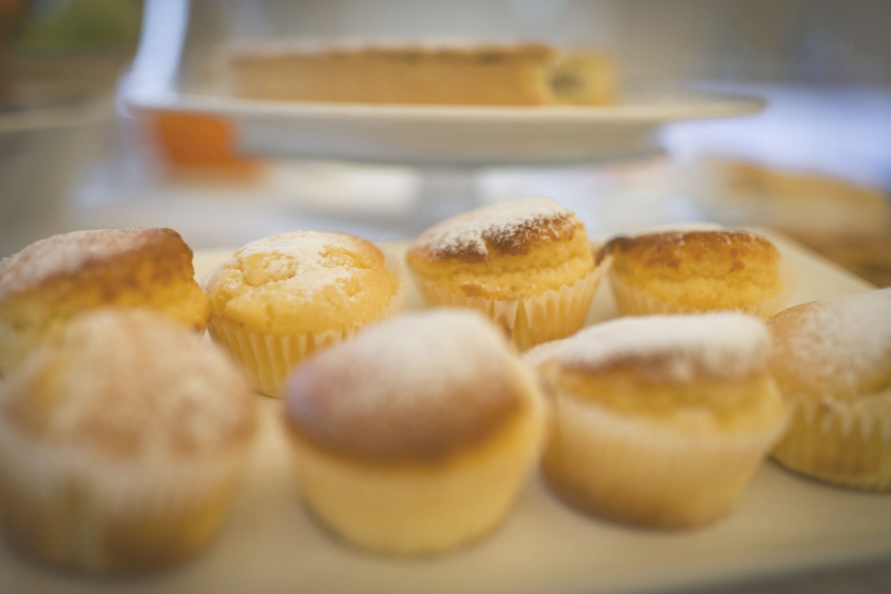 A tray of muffins with powdered sugar on a table.