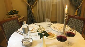 A dining table set with plates, glasses, a bottle, and a candle.