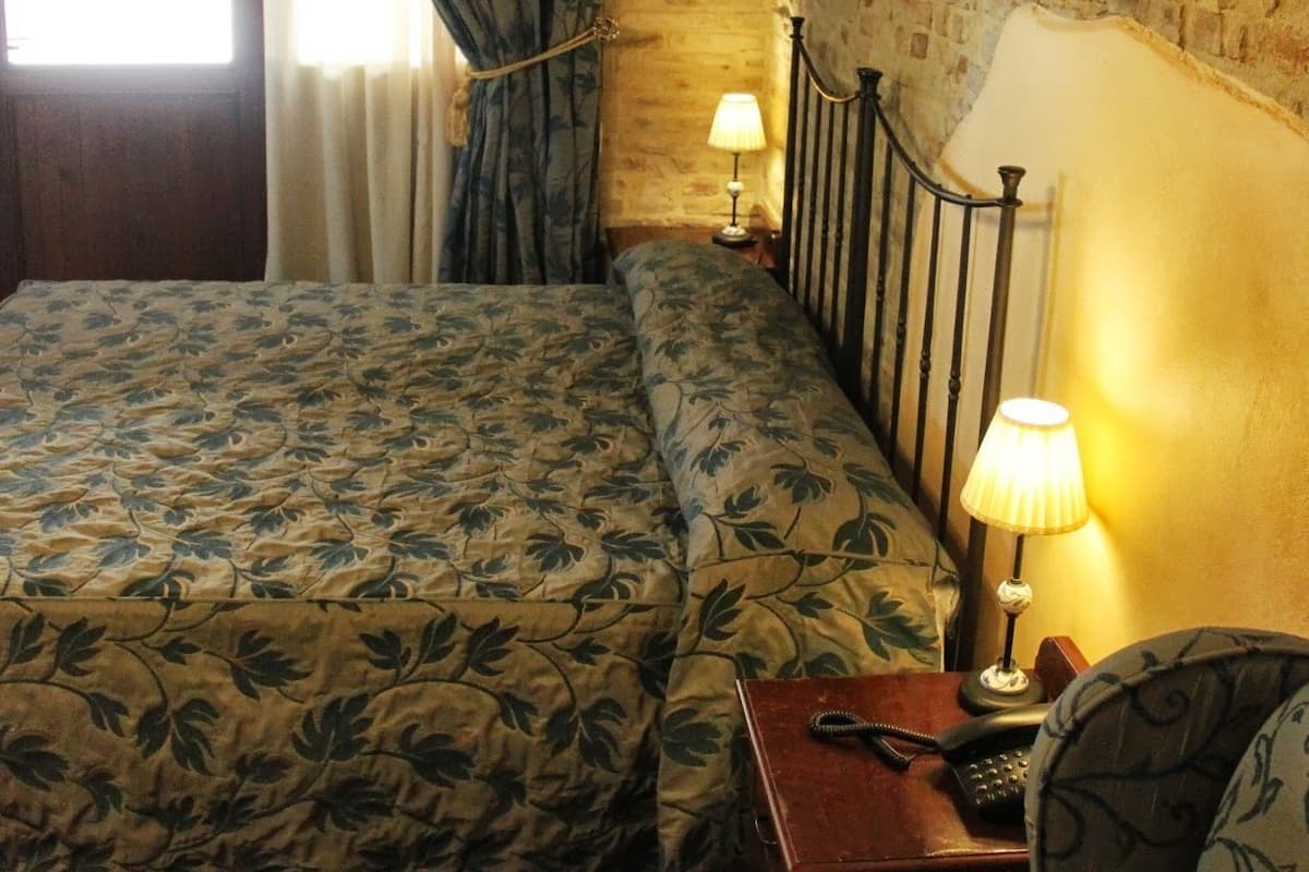 A bedroom with a bed, two bedside lamps, a telephone, and a patterned rug.