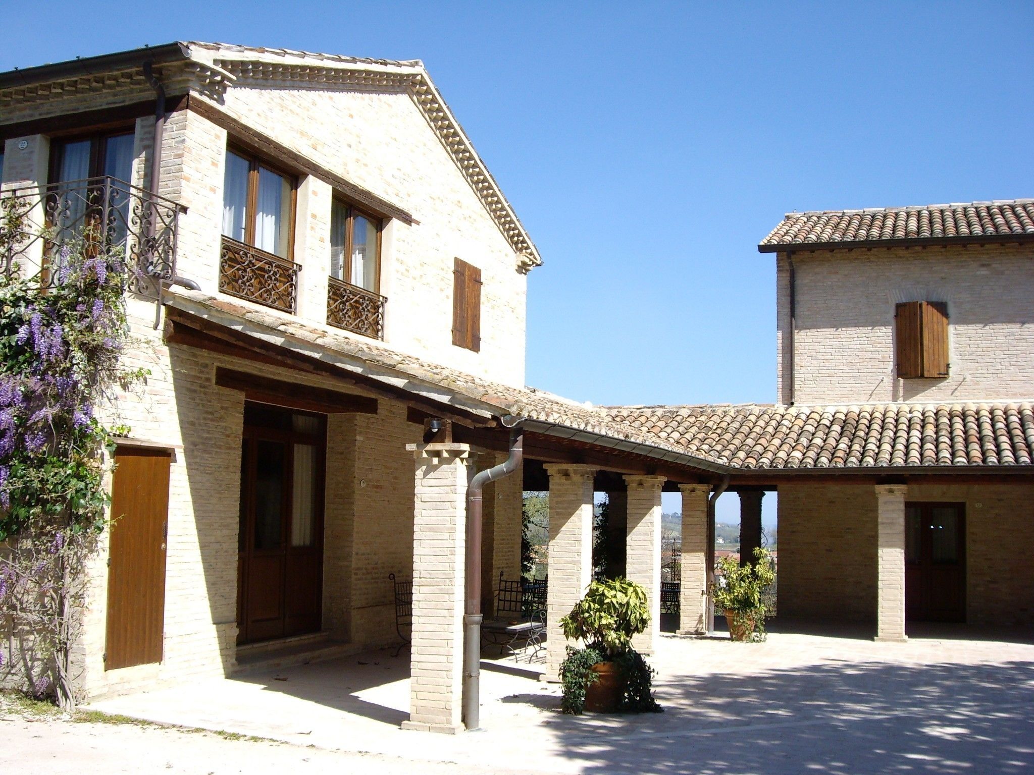 A traditional building with a courtyard, featuring a covered patio area with columns and potted plants.