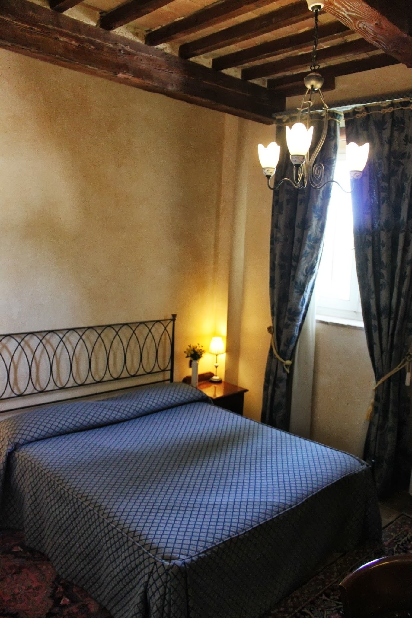 Una camera da letto con un letto, un comodino, una lampada e una finestra con tende.