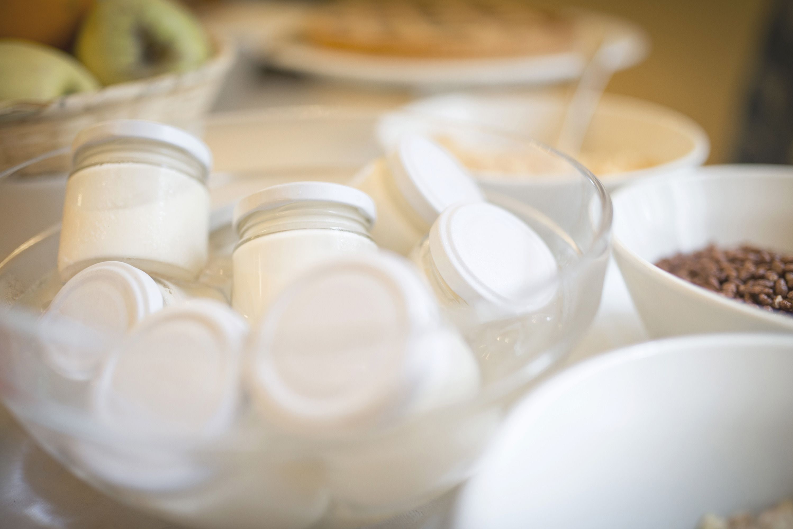 A close-up of various kitchen items including jars, a measuring cup, and bowls on a table.