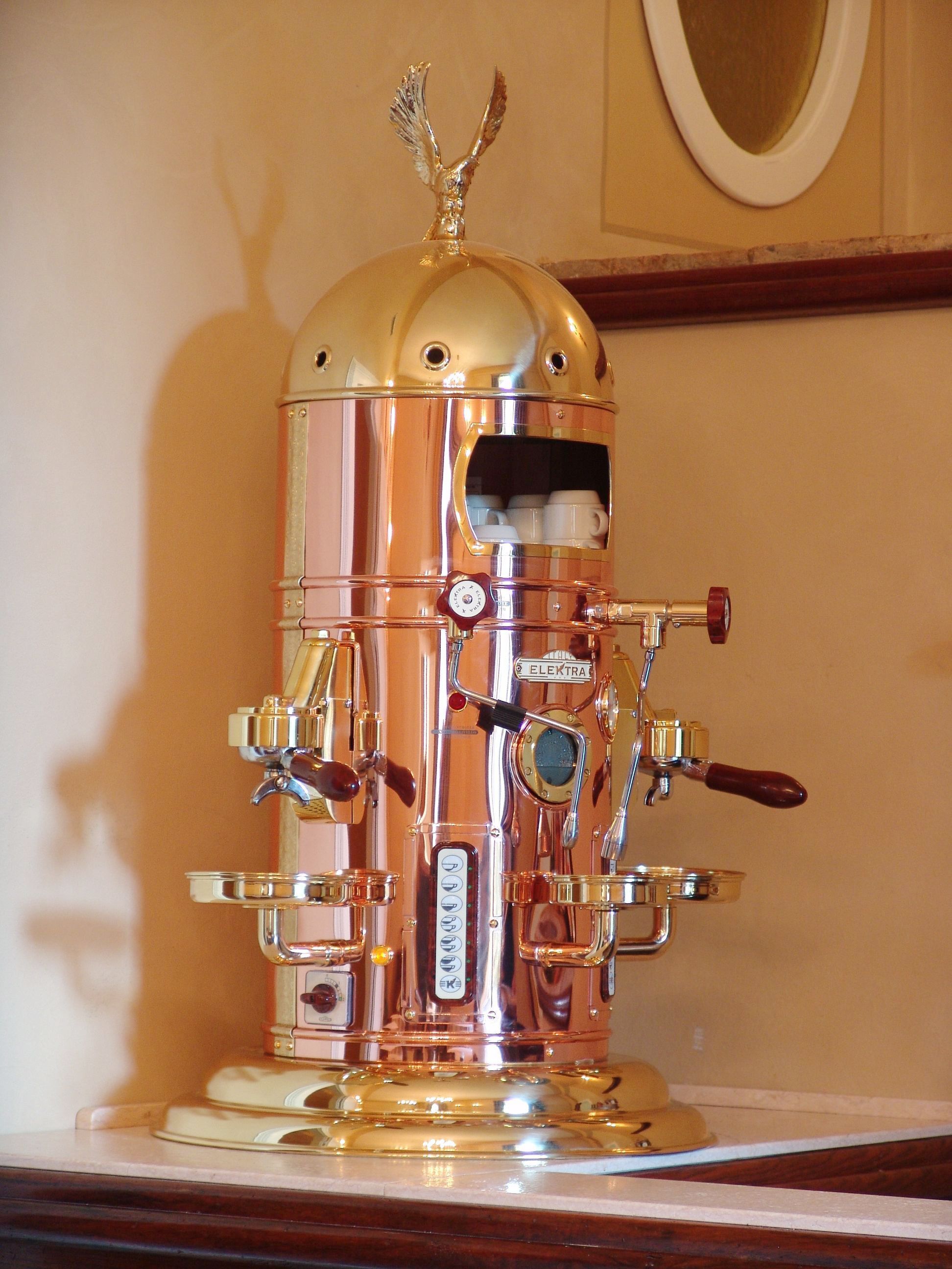 Eine alte Espressomaschine mit Messingbeschichtung, einer Bedienfeld und einem Ausguss.