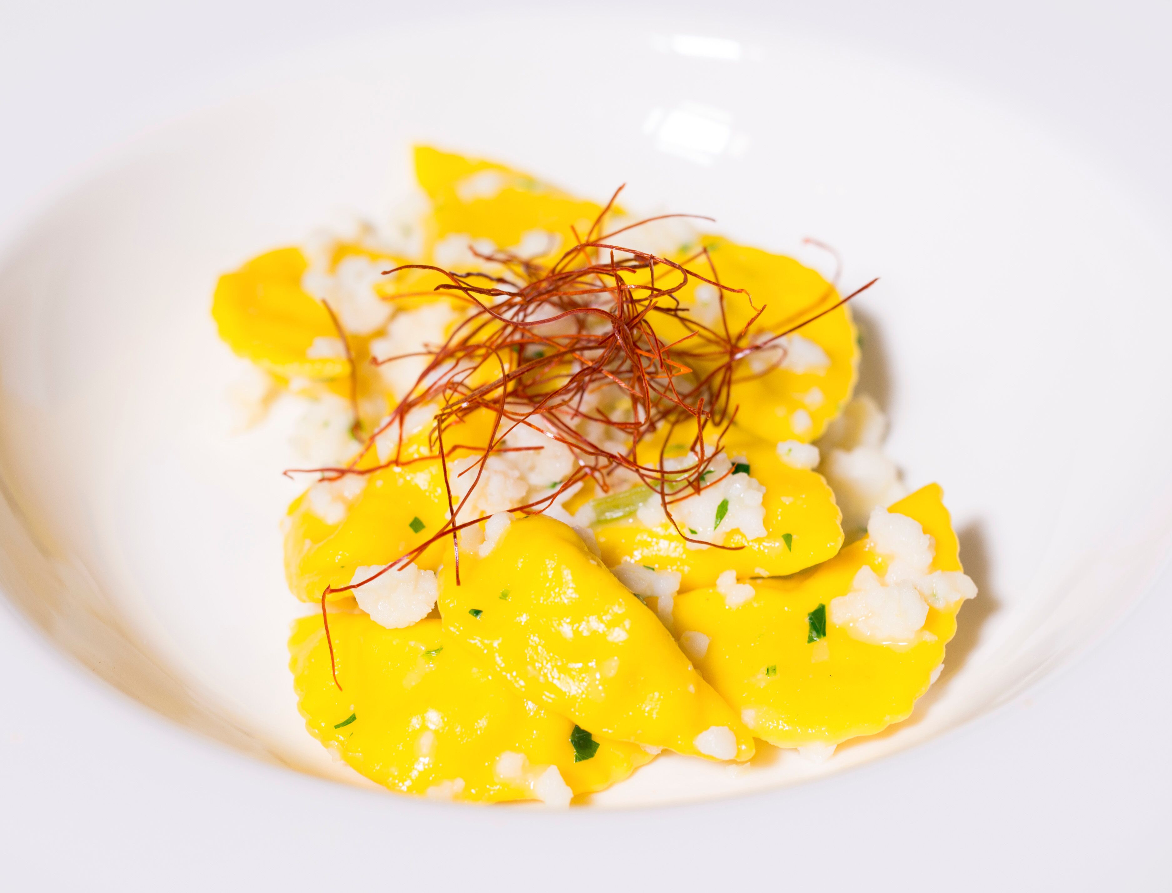 Un plato con lonchas de mango amarillo, queso blanco y hebras rojas, posiblemente azafrán.