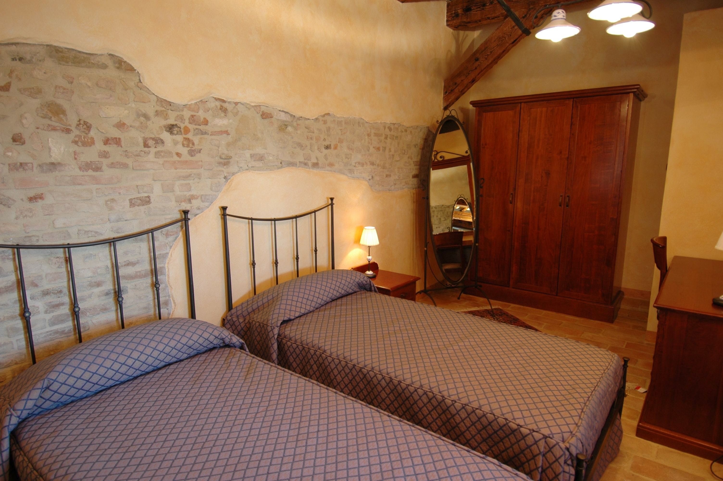 Un dormitorio con dos camas, un armario de madera, un espejo y una mesita.