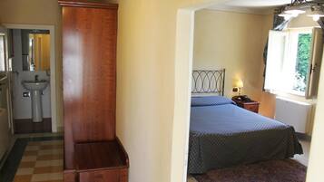 Ein Schlafzimmer mit Bett, Nachttisch, Lampe und Fenster.