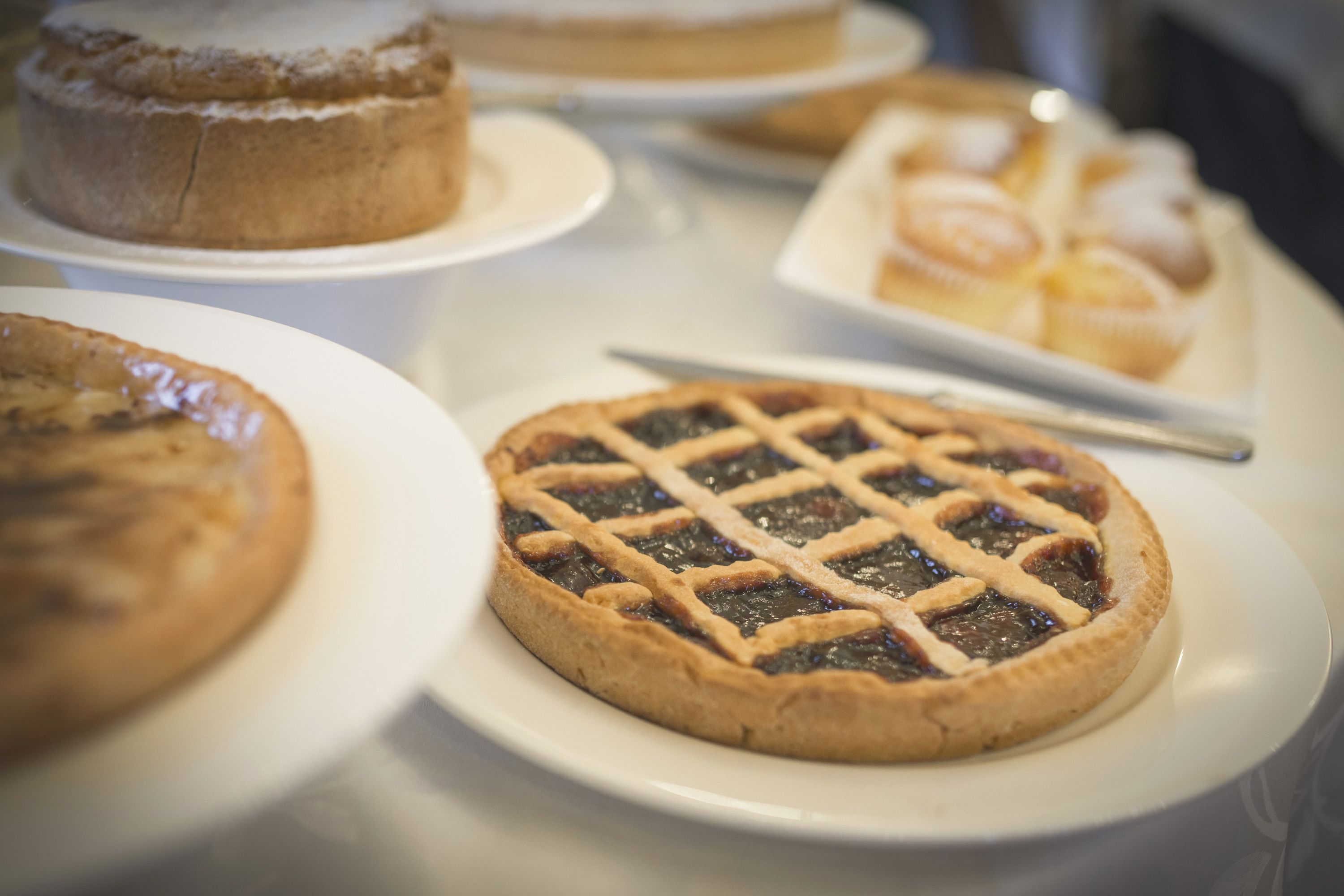 Verschiedene Desserts auf weißen Tellern, darunter Kuchen und Muffins.