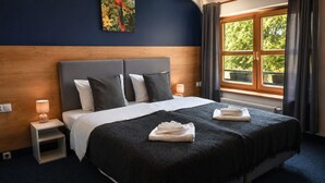 A bedroom with a bed, nightstands, a window, and a painting on the wall. - Dom Oliwski (Gdansk)