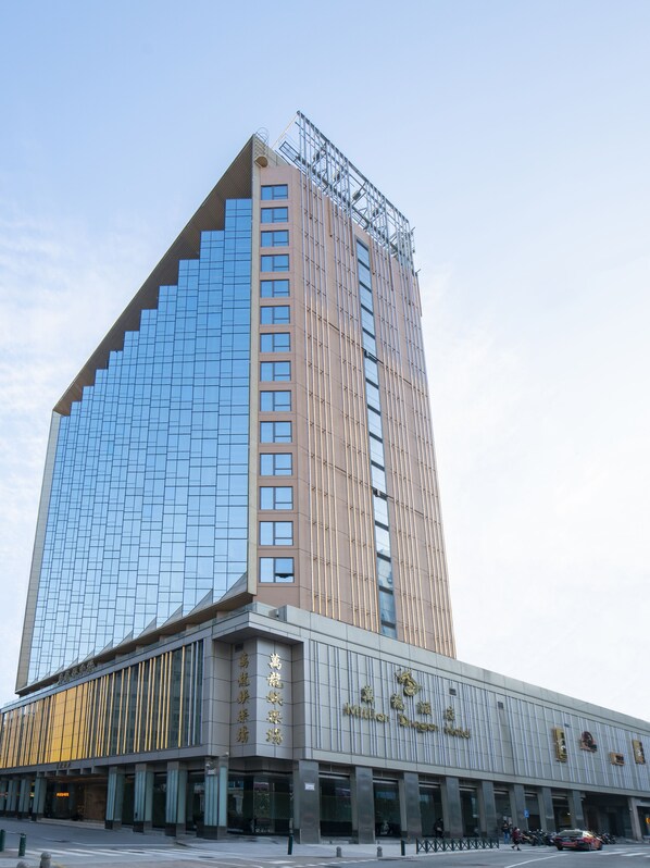 A modern hotel with a glass facade and a traditional building section below.