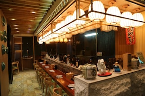 A restaurant with a long wooden counter, multiple chairs, and hanging paper lanterns. - City Viva Hotel Macau (Macau)