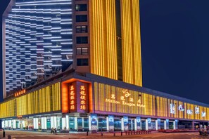 A modern building with illuminated signage and vertical light strips. - City Viva Hotel Macau (Macau)