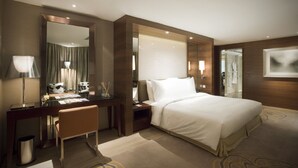 A modern hotel room with a large bed, a desk with a chair, a vanity with a mirror, and a large window with blinds. - City Viva Hotel Macau (Macau)