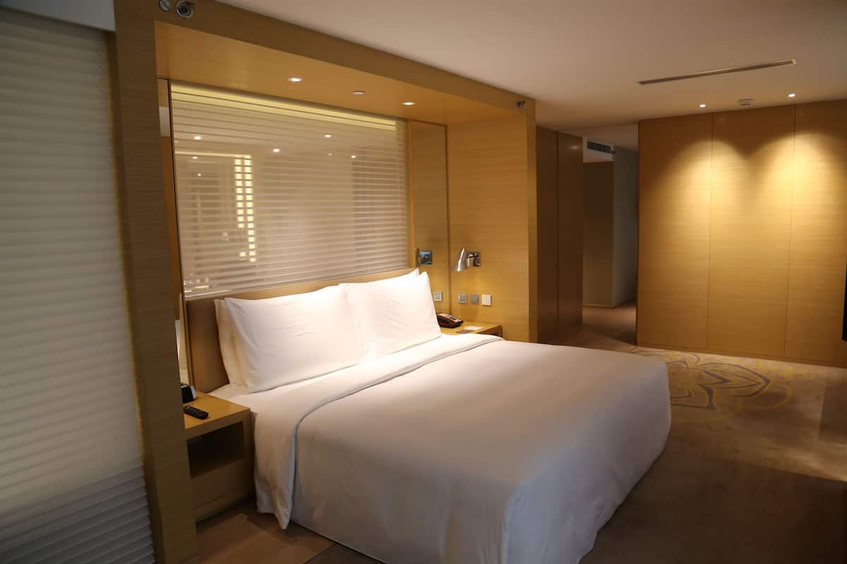Una habitació d'hotel moderna amb un llit gran, una taula de nit i una làmpada penjada a la paret.