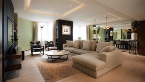 A modern living room with a sectional sofa, a coffee table, and a dining area with a table and chairs. - City Viva Hotel Macau (Macau)
