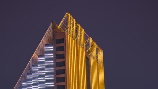 A modern building with vertical yellow lighting and a sloped roof. - City Viva Hotel Macau (Macau)