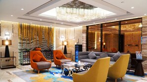 A modern lobby with a sofa set, two armchairs, a coffee table, and a chandelier. - City Viva Hotel Macau (Macau)