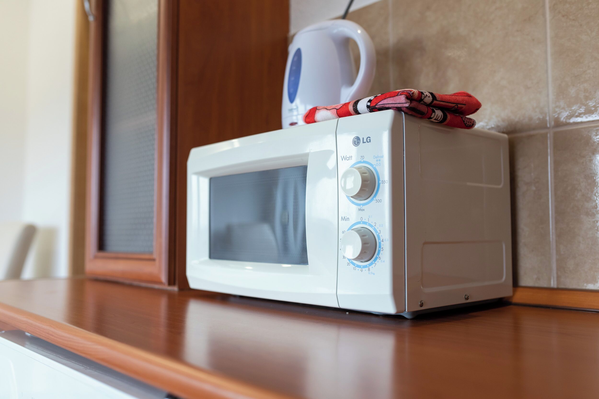 Un microondas blanco sobre una encimera de madera, con pantalla digital y dos perillas de control.
