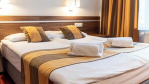 Hotellihuone, jossa on suuri sänky, kaksi tyynyä, yöpöytä ja lamppu.