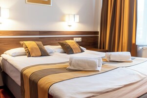 Habitación de hotel con una cama grande, dos almohadas, una mesita de noche y una lámpara.