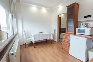 Une cuisine compacte comprenant une table à manger, des chaises, un four à micro-ondes, un réfrigérateur et un placard.