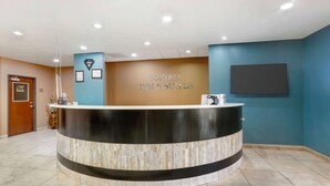 A reception area with a curved reception desk, a wall-mounted TV, and framed certificates.