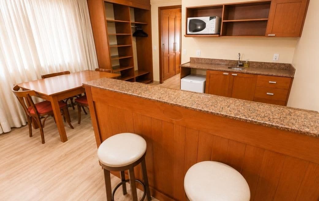 A compact kitchen with wooden cabinets, a granite countertop, and a microwave.