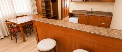 A compact kitchen with wooden cabinets, a granite countertop, and a microwave.