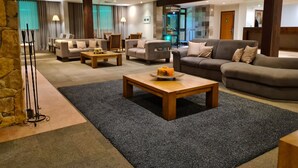 Un moderno vestíbulo de hotel con un área de descanso, una recepción y una escalera que conduce a los pisos superiores.