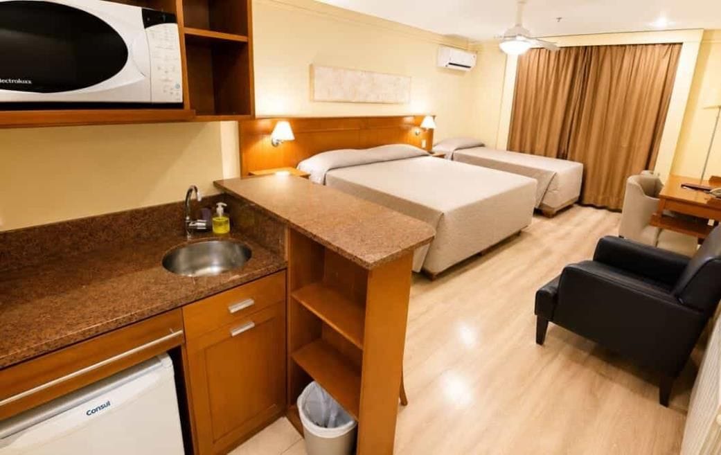 Habitación de hotel con kitchenette, dos camas, un escritorio y una silla.