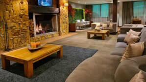 Una sala de estar acogedora con chimenea de piedra, asientos cómodos y un televisor de pantalla plana montado en la pared.