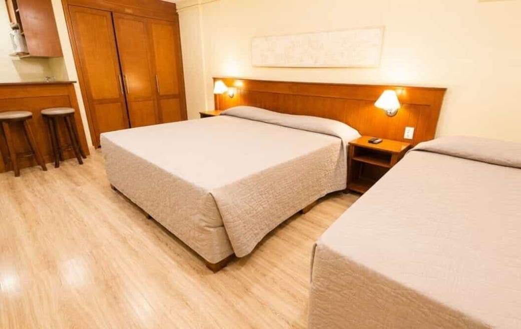 Ein Hotelzimmer mit Bett, Nachttisch, Lampe und einem Holzschrank.