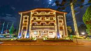 Un hotel con fachada simétrica, varios balcones y una entrada bien iluminada.