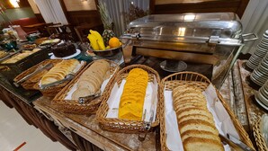 Un bufé con diversas opciones de comida, incluyendo pan, pasteles y frutas.