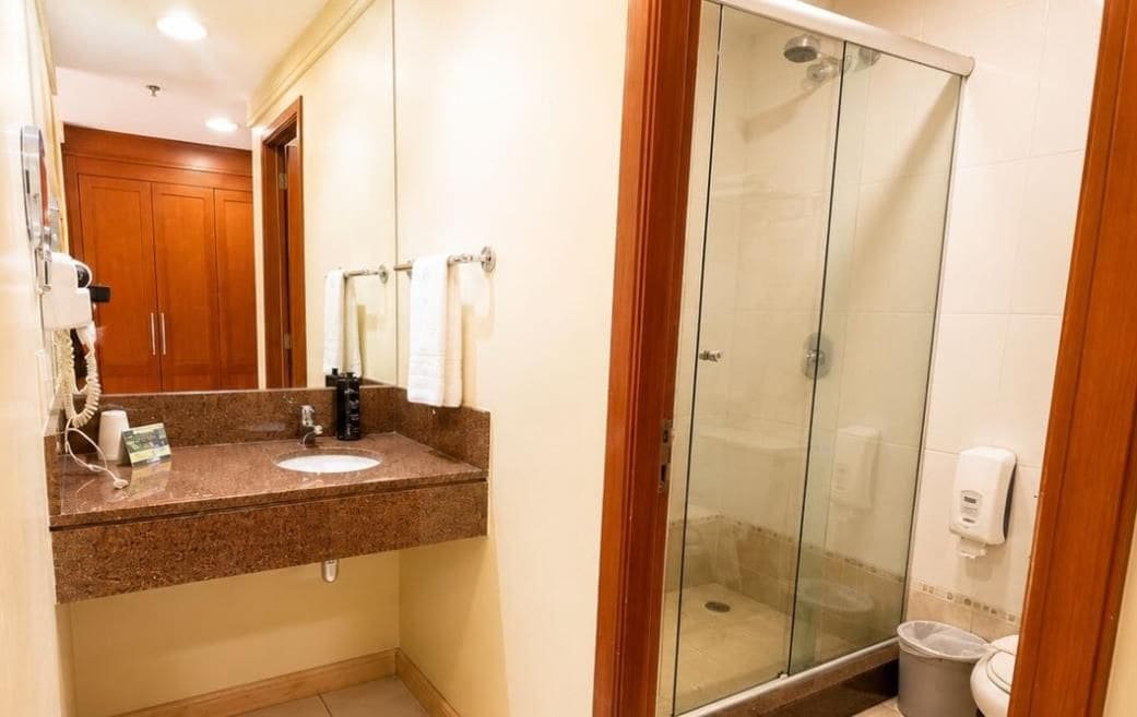 Een badkamer met een granieten aanrechtblad, een douchecabine met glazen wanden en een toilet.