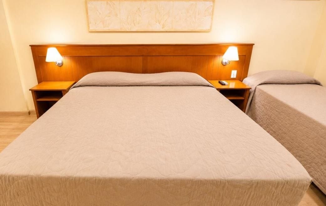 A double bed with a wooden headboard, two bedside tables with lamps, and a wall-mounted artwork.