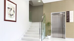 Un interno moderno con una scala, una pianta in vaso e un ascensore.