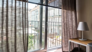 Una habitación con un ventanal grande, una mesa con lámpara y vistas a edificios.