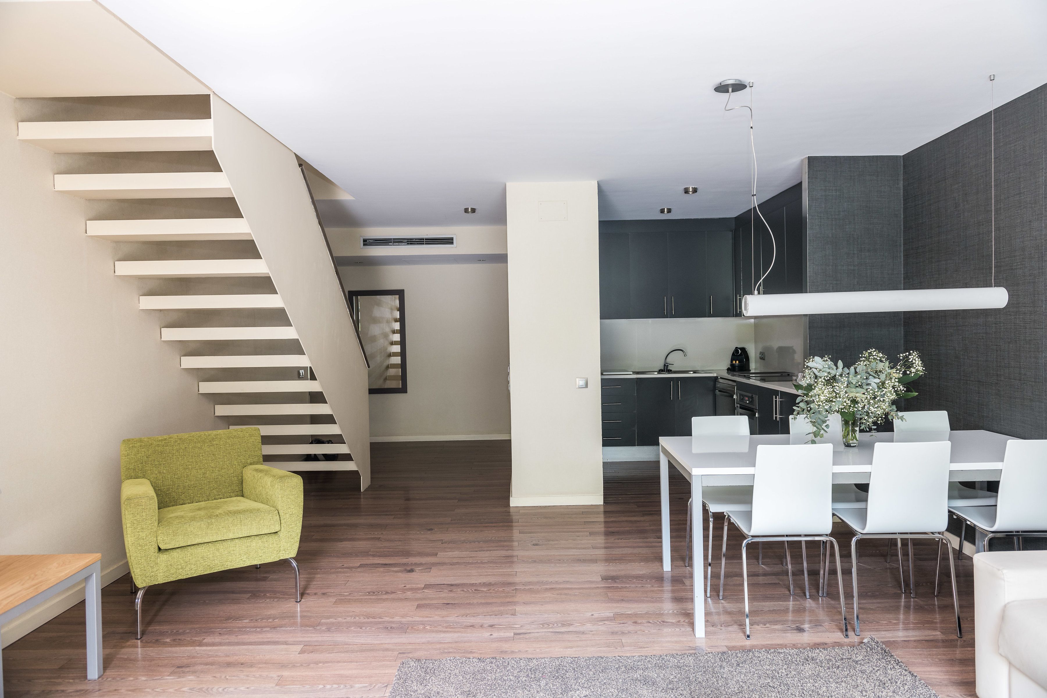 Een modern interieur met een trap, een eethoek en een keuken.