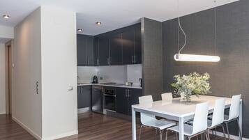 Una cocina moderna con armarios oscuros, una mesa de comedor blanca y una lámpara colgante.