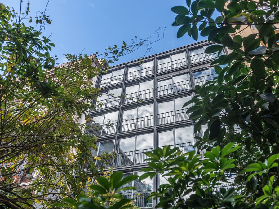 A modern building with multiple floors, large windows, and balconies.