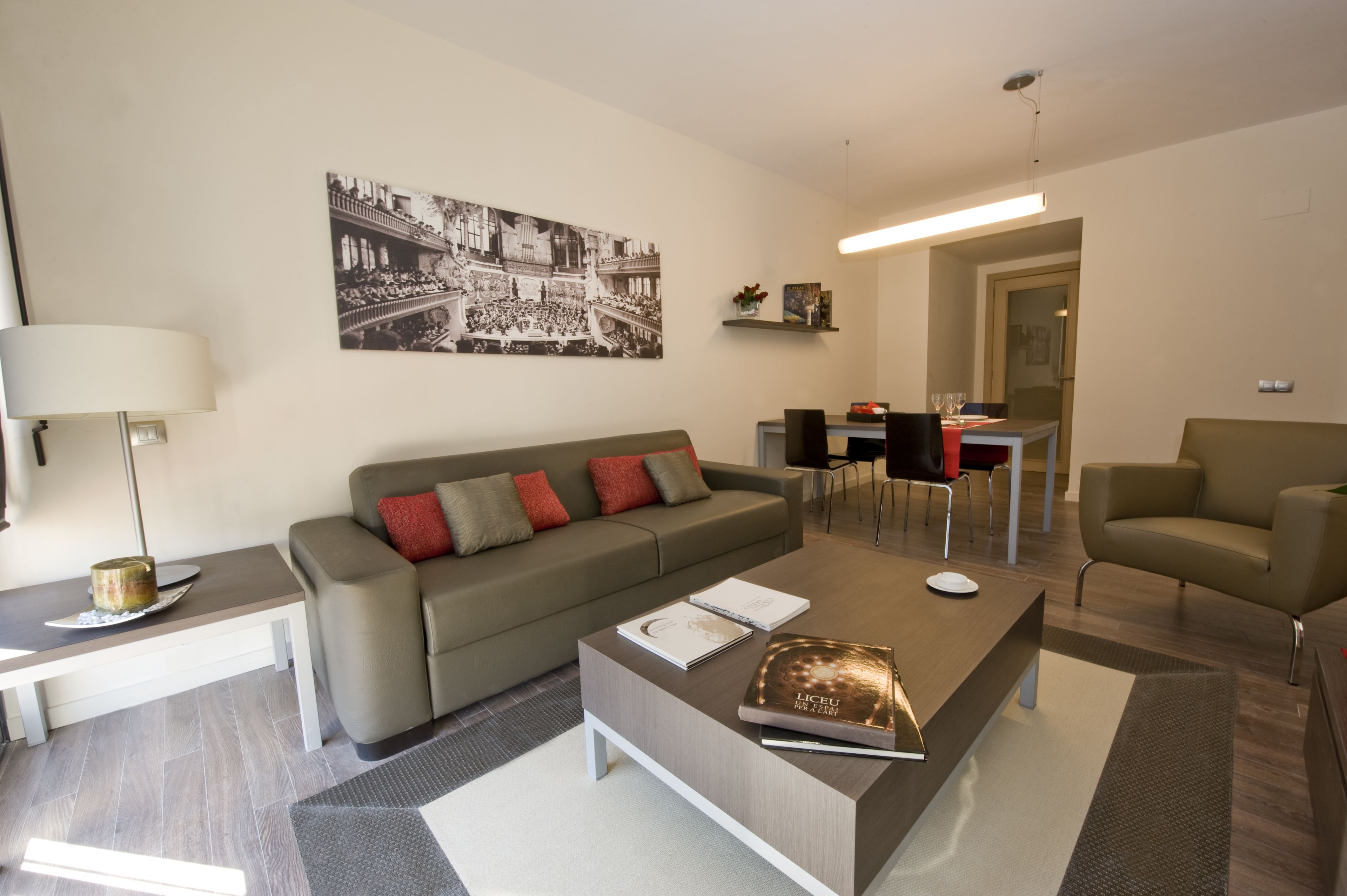 A modern living room with a sofa, coffee table, and a dining area with chairs and a table.