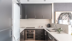 Una cocina moderna con electrodomésticos de acero inoxidable, armarios grises y piso de madera.