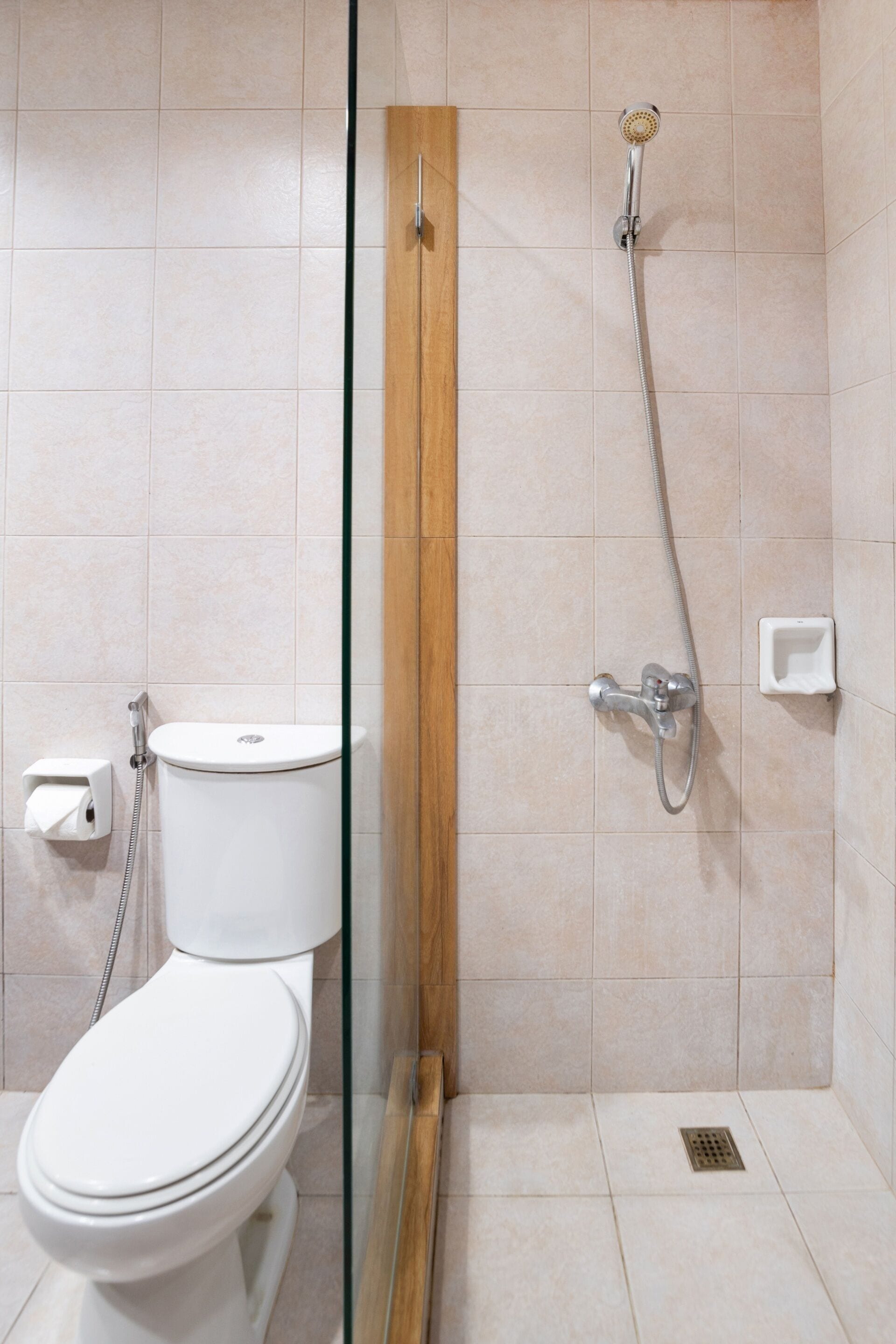 A modern bathroom with a glass-enclosed shower, a toilet, and a small sink.