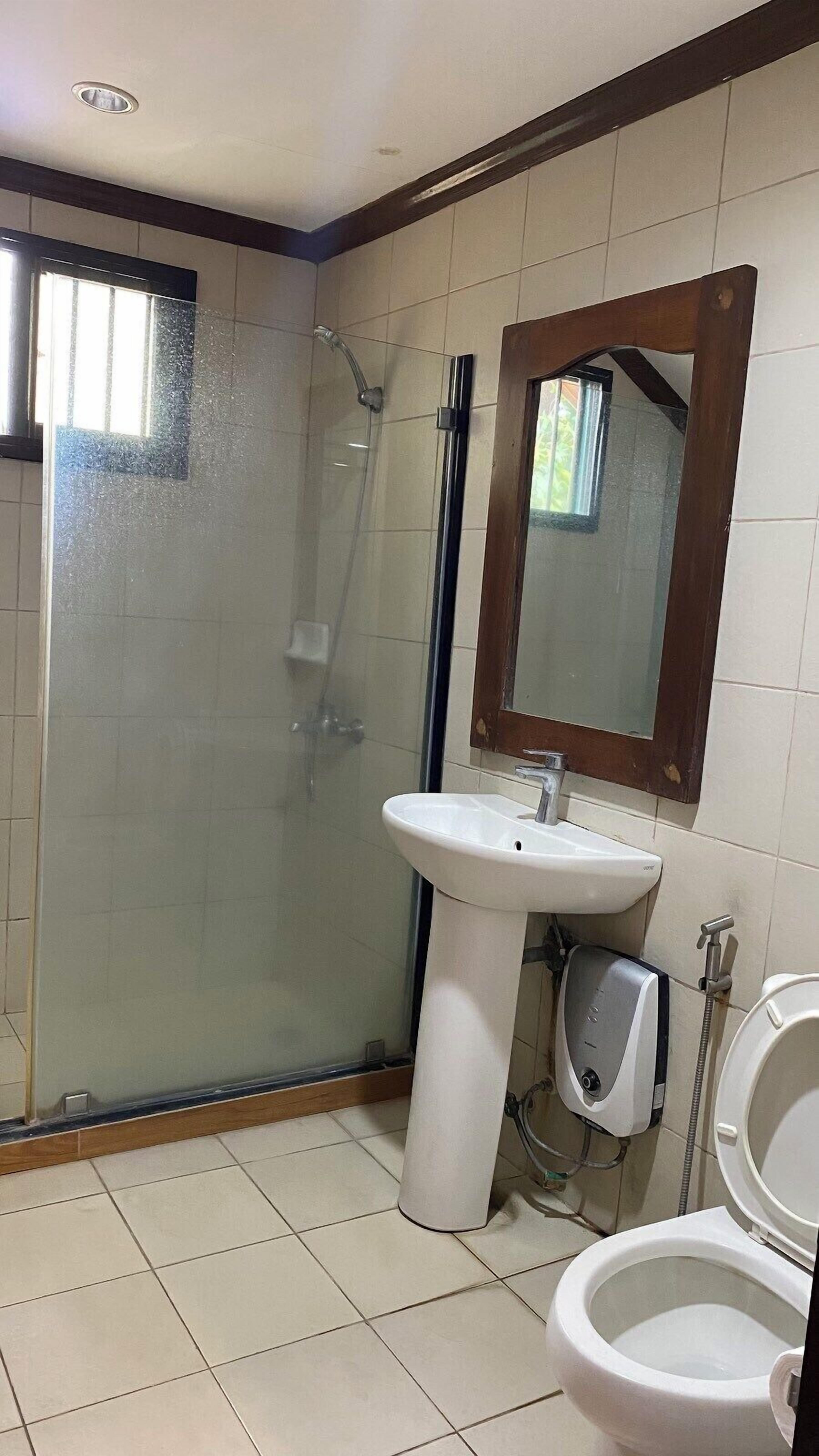 A bathroom with a glass-enclosed shower, a pedestal sink, a toilet, and a mirror.