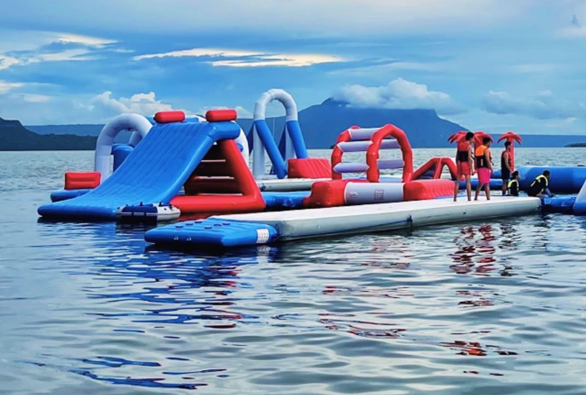An inflatable water park with slides and play structures on a lake.