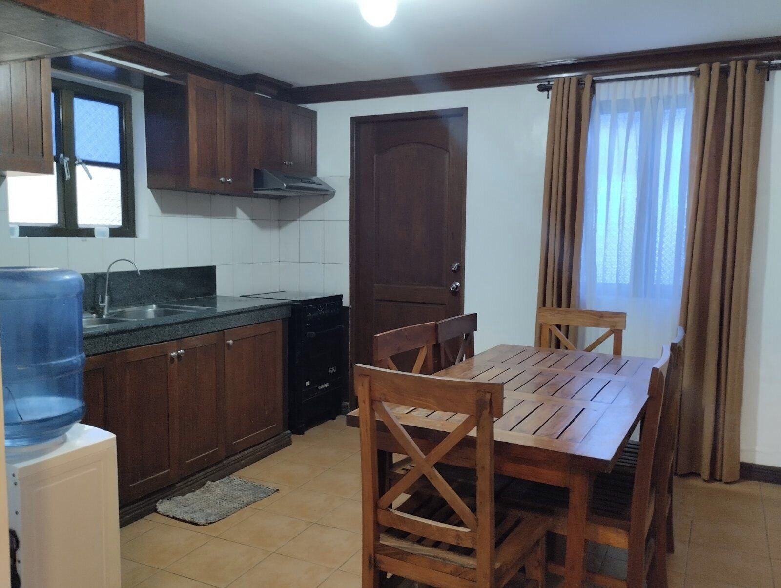 A compact kitchen with wooden cabinets, a built-in oven, and a dining table with chairs.
