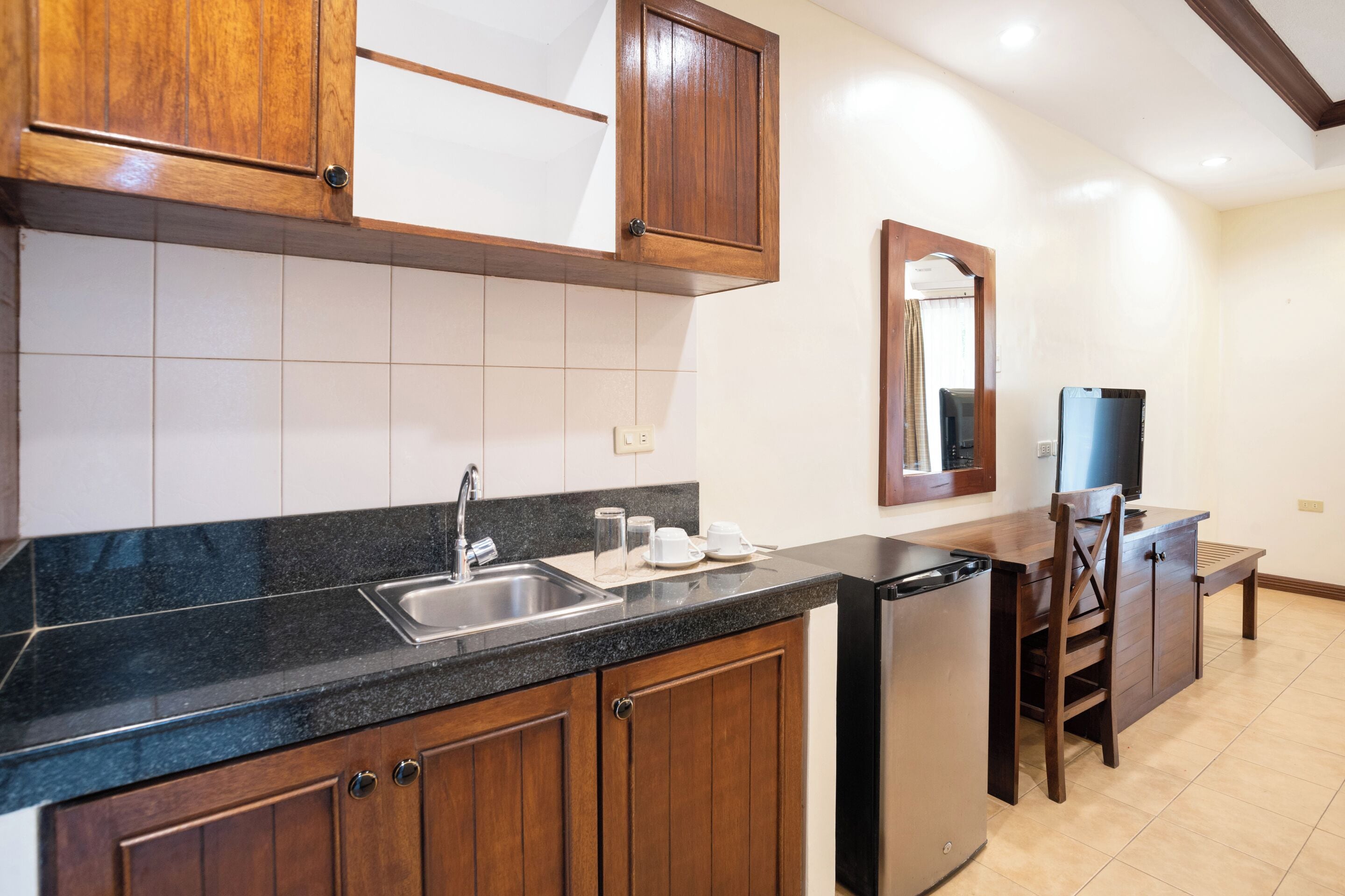 A kitchen with wooden cabinets, a black countertop, a sink, and a dishwasher.