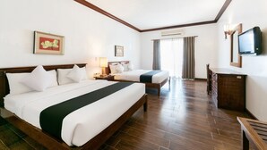 Ein Hotelzimmer mit zwei Betten, Holzboden, Fernseher und Schreibtisch.
