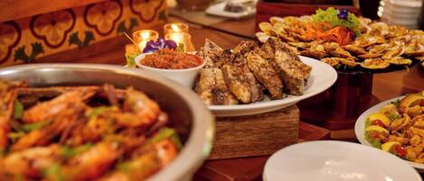 Un bufé con diversos platos, incluyendo carnes a la parrilla, mariscos y ensaladas.